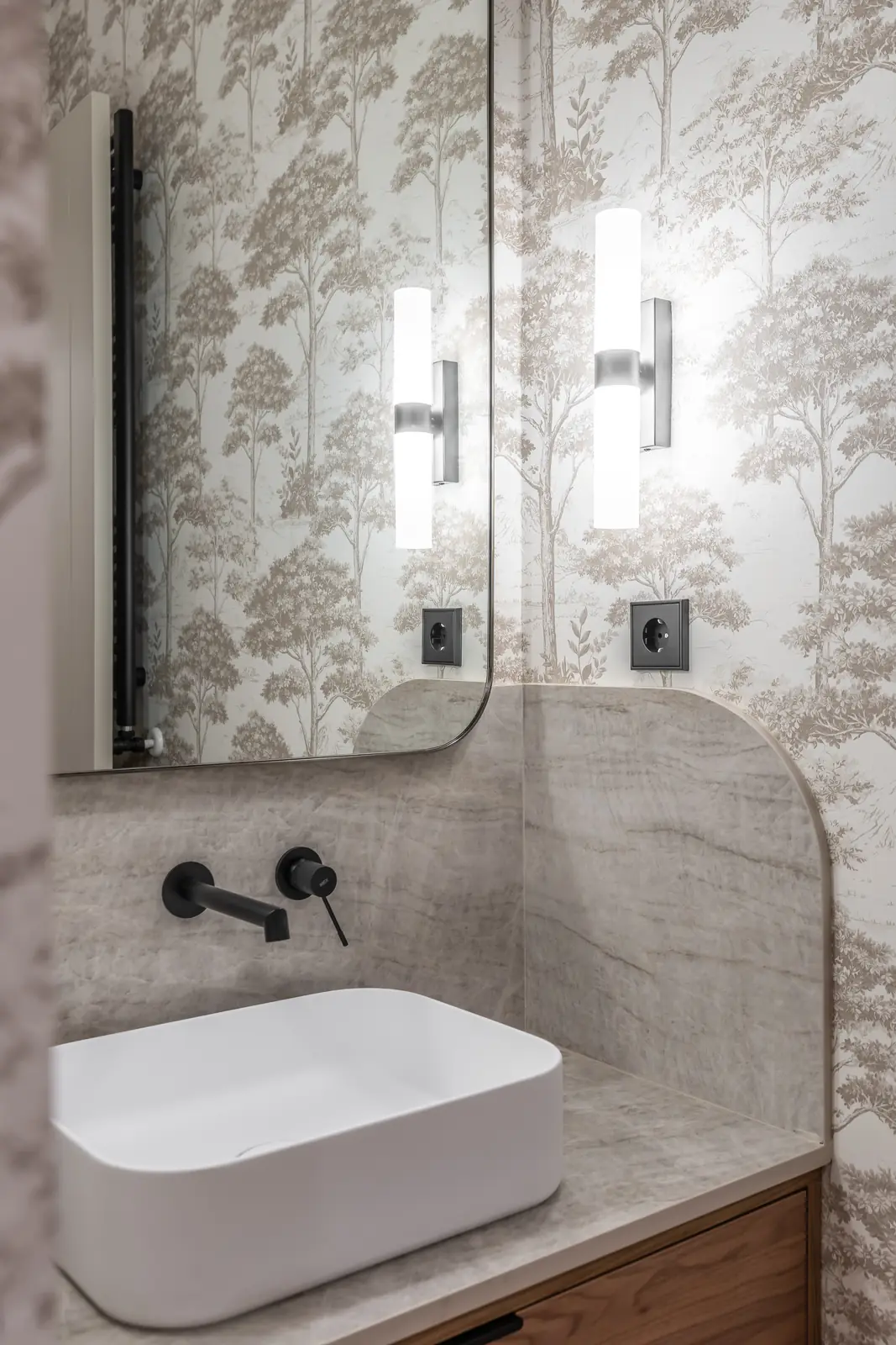 Baño con papel pintado botánico, lavabo sobre encimera y grifería negra