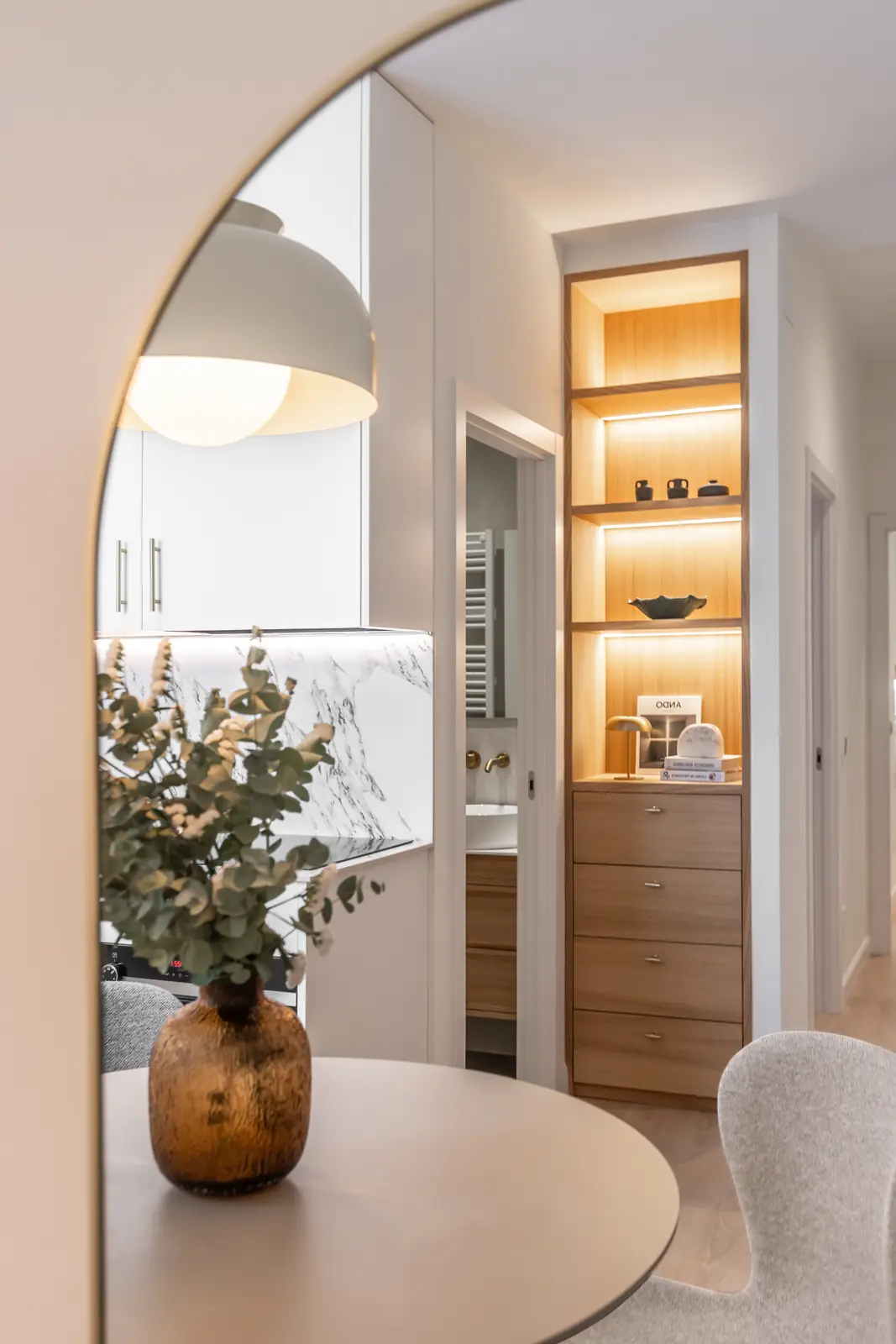 Cocina con acceso en arco, hornacinas iluminadas y mesa redonda