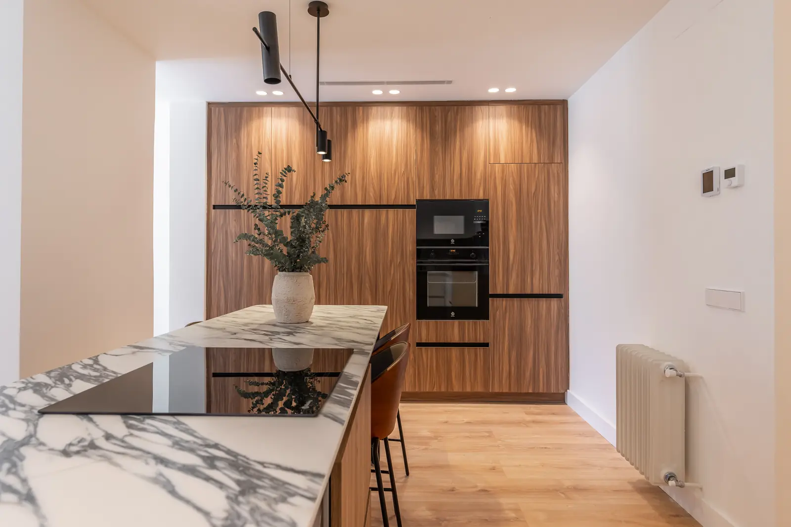Cocina de madera con isla de mármol y columna de horno negra