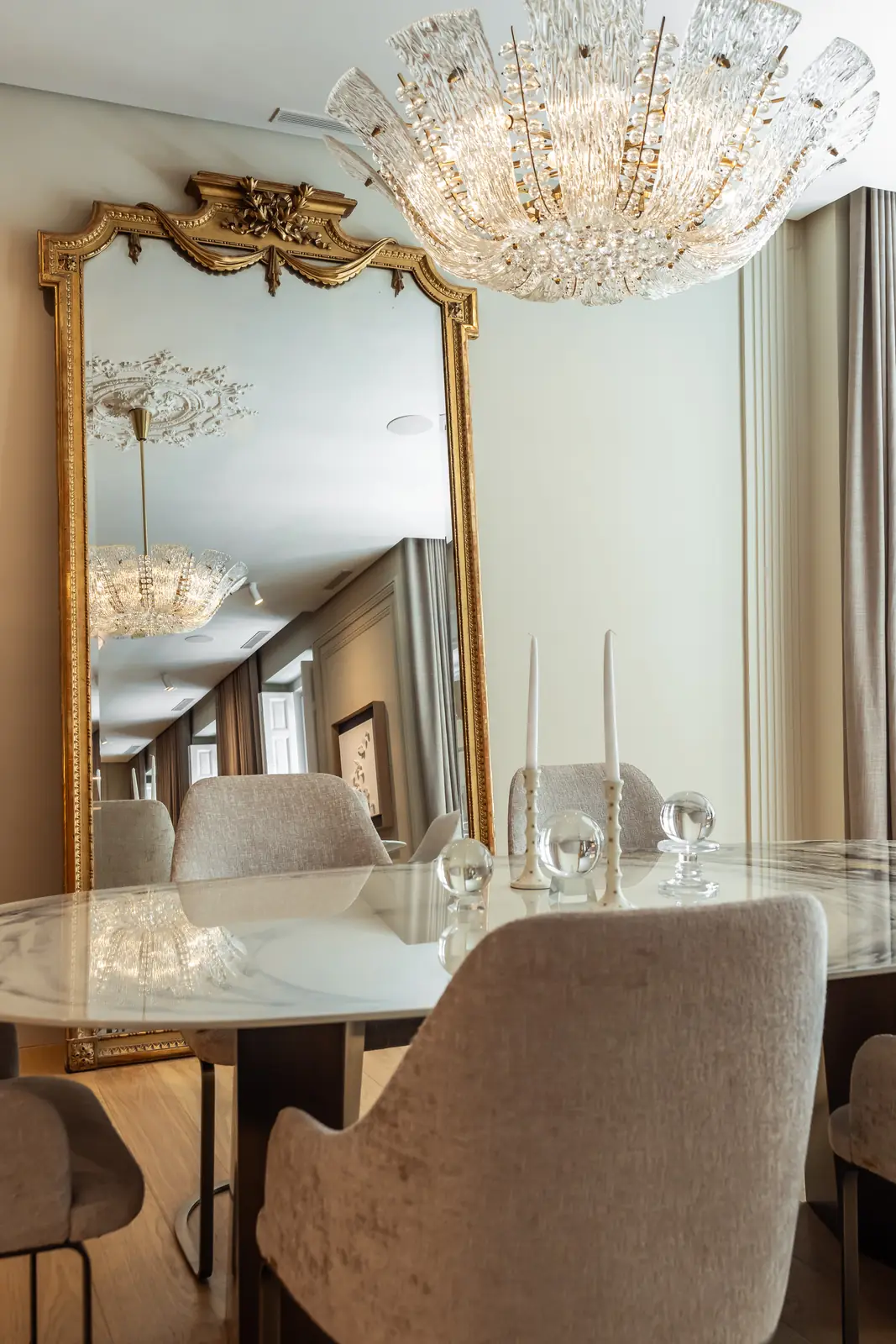 Comedor elegante con gran espejo dorado y lámpara de araña de cristal
