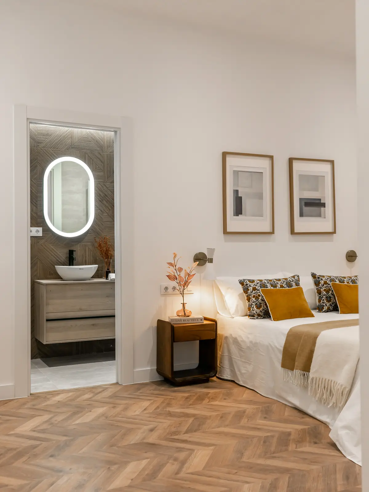 Dormitorio con baño en suite y suelo de espiga en madera