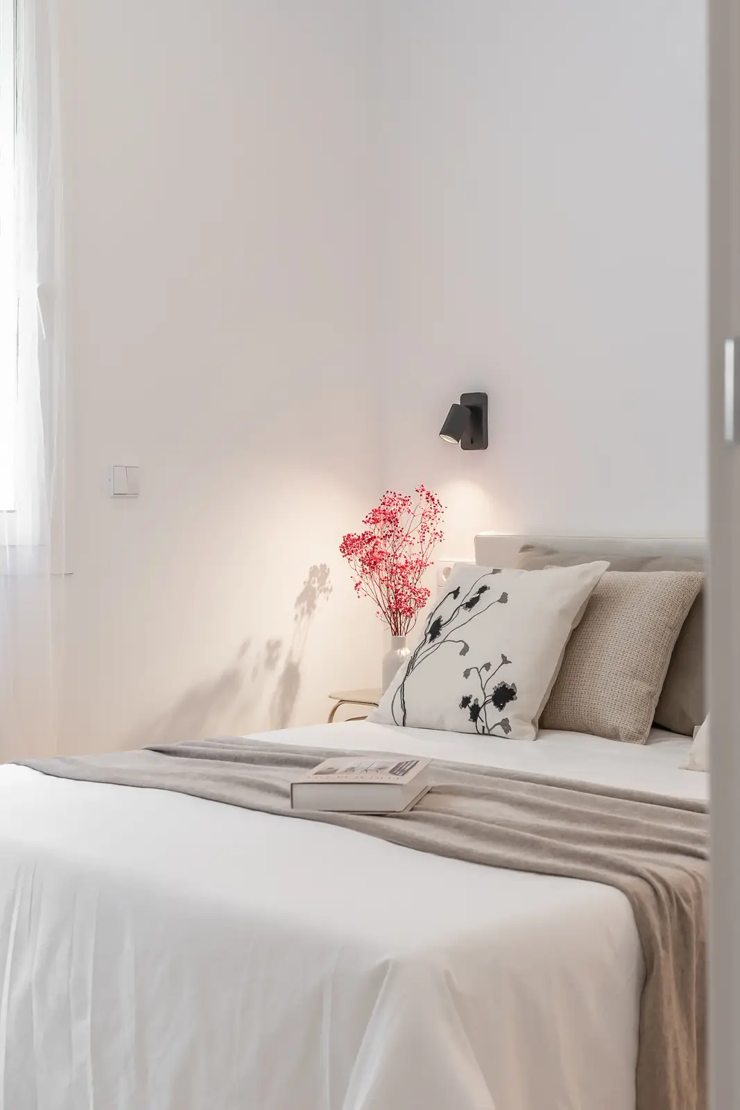 Dormitorio minimalista en blanco con cama y detalle floral