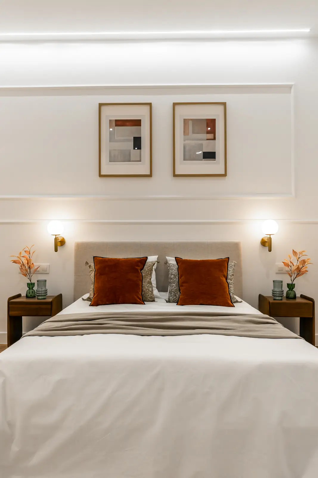 Dormitorio con cama, apliques de pared y cojines naranjas
