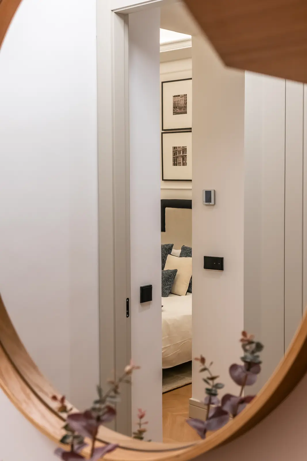 Pasillo con espejo redondo que refleja el dormitorio