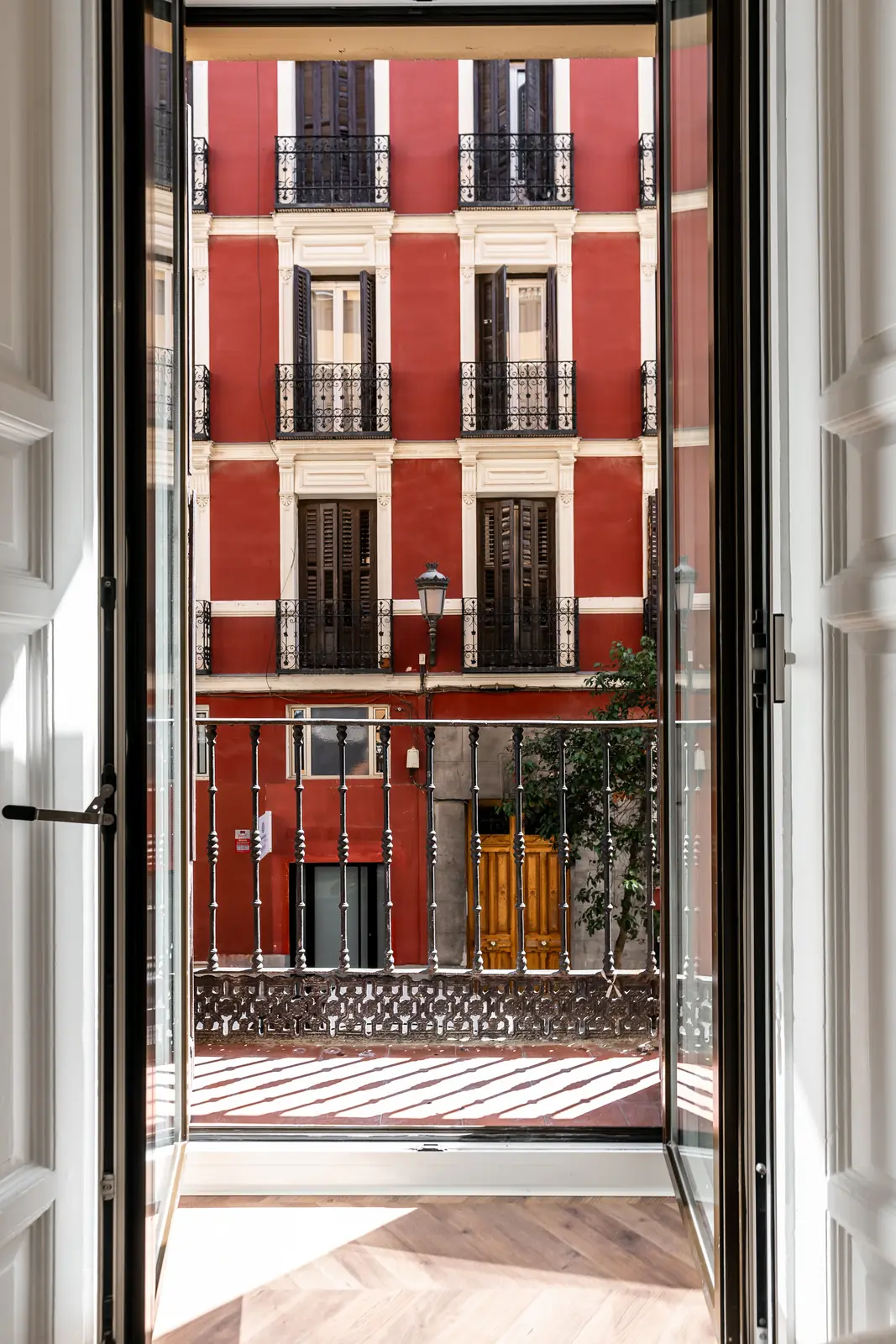 Balcón abierto con vistas a fachada clásica madrileña de ladrillo rojo