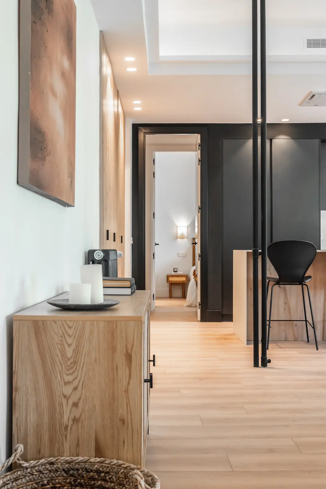 Espacio integrado de salón y cocina con aparador de madera y detalles negros