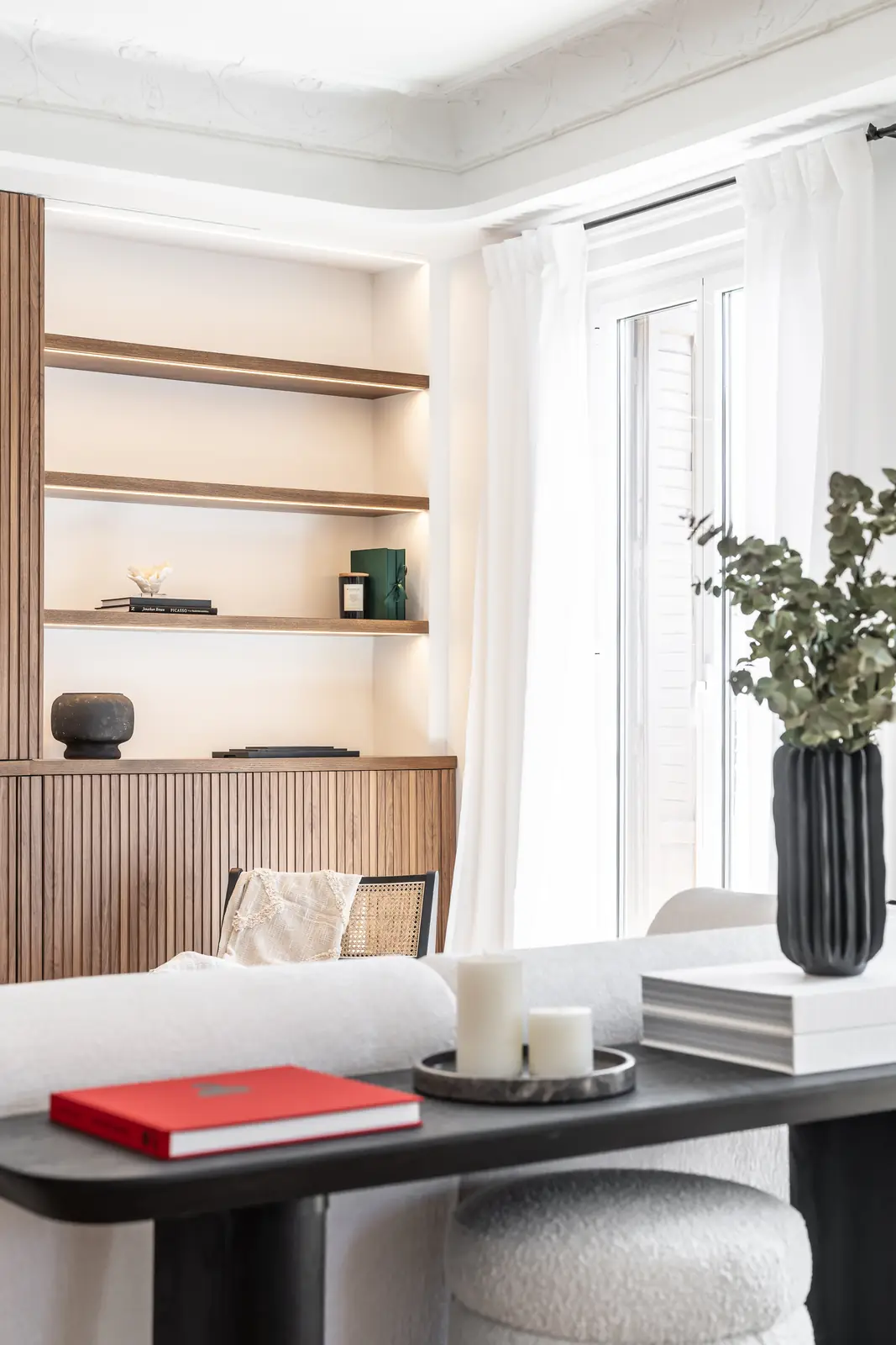 Salón luminoso con estantería de lamas de madera y sofá blanco