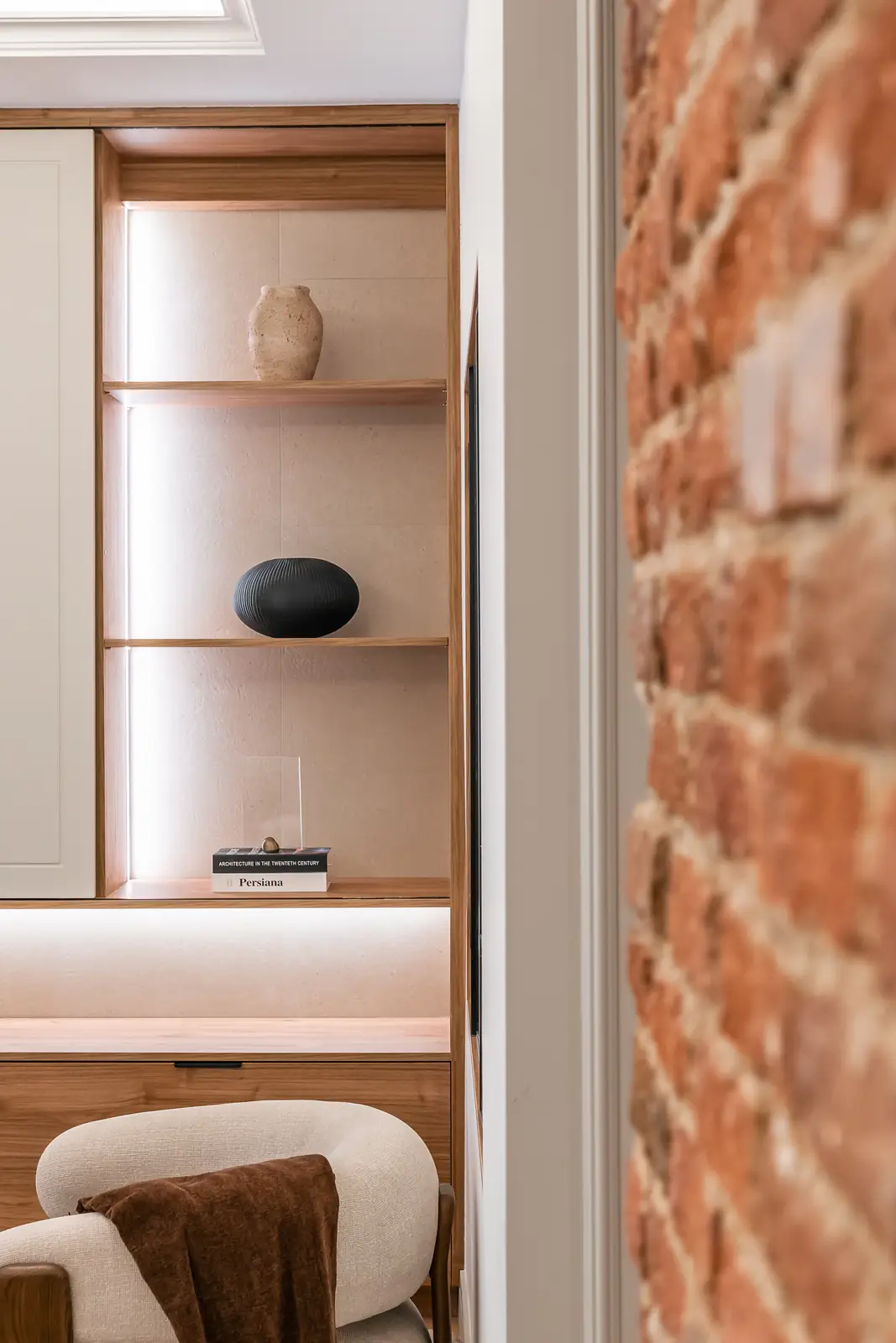 Salón con estantería de madera iluminada y pared de ladrillo visto