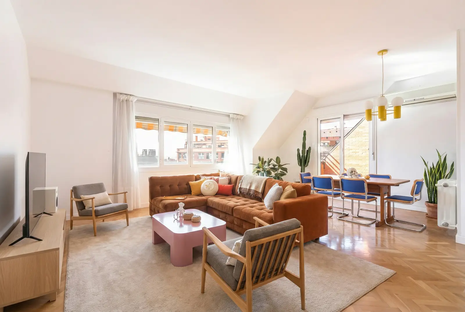 Salón abuhardillado con home staging virtual: sofá de cuero y sillones de diseño