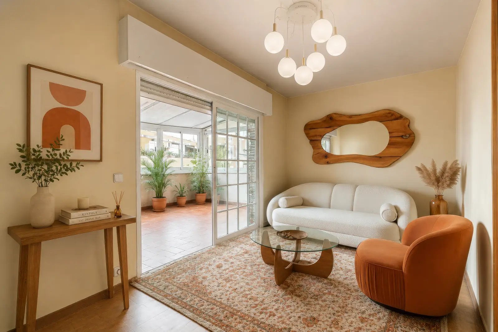 Salón luminoso con home staging virtual: sofá curvo blanco, sillón terracota y espejo